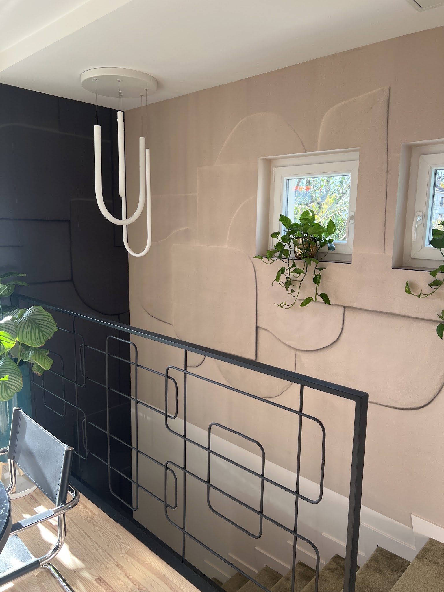 Mur à relief rose poudré et mur noir dans une cage d'escalier